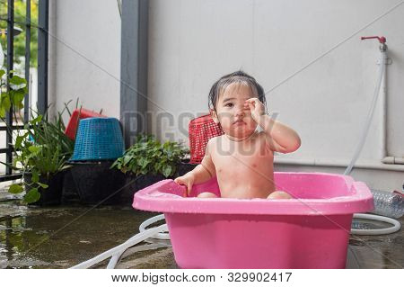 Asian Woman Washing Her Daughter In Bathtub, Baby Girl Taking A Bath In Pink Tub