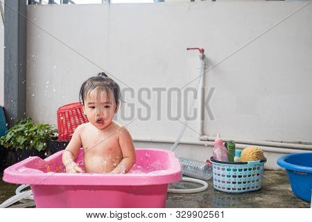 Asian Woman Washing Her Daughter In Bathtub, Baby Girl Taking A Bath In Pink Tub