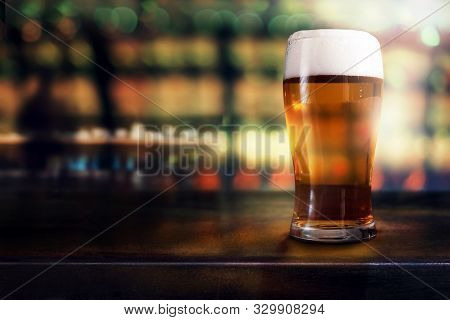 Glass Of Beer On Table In Bar Or Restaurant. Side View. Night Scene