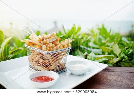 French Potato Fries On Metal Mesh Flying Sieve With Two Dipping Sauce, Served On Rustic Wooden Table