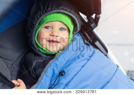 Portrait Of Cute Caucasian Toddler Boy In Black Hooded Warm Insulated Dawn Overall Jacket And Blue B