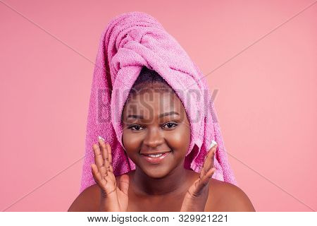 Young Woman Standing On Towel Tied On Head With Hands Under Chin In Studio Pink Backhround