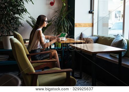 Businesswoman Sits At A Table In The Office And Looks At A Tablet Pc. Mosk Up