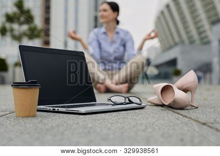 On The Tile Is An Open Laptop, A Pair Of Women's Shoes, A Brown Cup Of Coffee With A Black Lid, And 