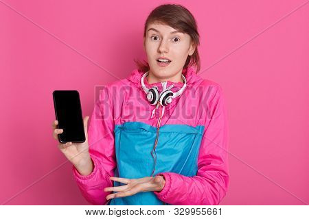 Cheerful Pretty Young Caucasian Sportswoman Holding Blank Screen Smartphone And Pointing On It Isola