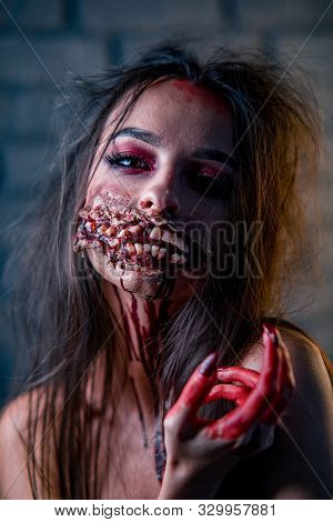 Woman In A Carnival Costume Of Bloody Mutant Or Vampire Stands With A Lot Of Ugly Teeth On The Face.