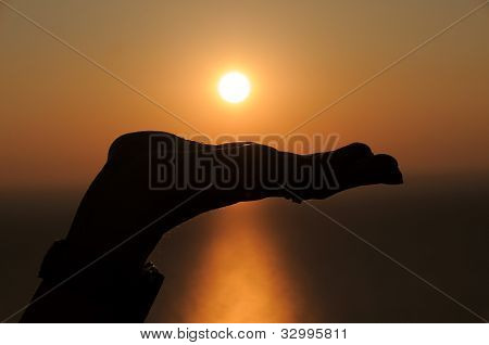 Una mano abierta frente al sol durante el atardecer
