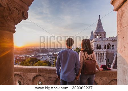 Young Couple Enjoy The View From The Point From Fisherman Bastion In Budapest During Sunrise.