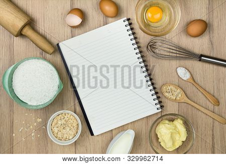 Tools And Ingredients  For Baking Cake (flour, Butter, Eggs, Milk, Oatmeal) And  Blank Notebook On W