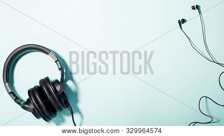 Headphones Of Different Types Flat Lay On Mint Color Background, Copy Space. Black In Ear Headphones