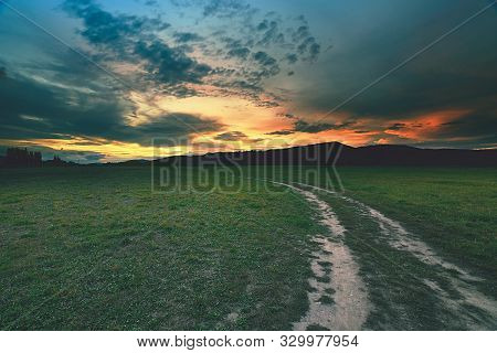 Rural Landscape With A Curved Road Between Meadows