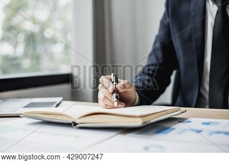 Businessman Takes Notes On A Topic That Examines Information From Finance Documents To Bring To Depa