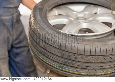 Mechanic Changing Tire In Car Service. Tire Rotation Machine.car Mechanic Mounts Tire On Wheel In A 