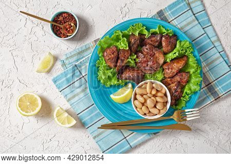 Chicken Liver Fry, Kaleji Fry, Served On Lettuce Leaves With Butter Beans And Lemon Wedges On A Blue