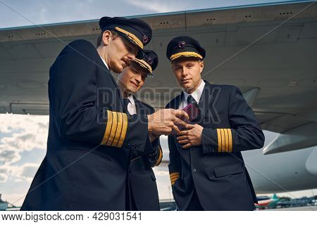 Three Airmen Viewing Photographs On The Smartphone