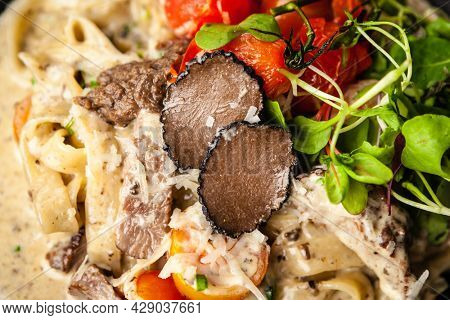 Black Angus beef tagliatelle pasta with fresh black truffles and parmegano. Delicious healthy traditional food closeup served for lunch in modern gourmet cuisine restaurant