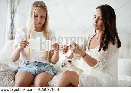 Woman hygene concept. Periods. Menstrual cycle. Mother explains daughter how to use hygiene pads and tampons. Woman and teenage girl talking at home.