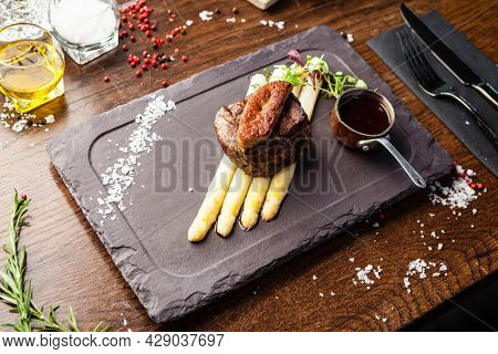 Tournedos Rossini. Foie gras, Black Angus beef tenderloin, white asparagus, red wine sauce. Delicious healthy traditional food closeup served for lunch in modern gourmet cuisine restaurant