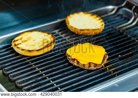 Cheese On Cutlet Grilling For Cheeseburger. Grilling Burger On Mangal. Two Burger Buns And One Cutle