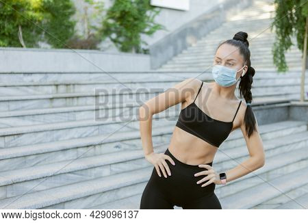 Young Slim Woman In Medical Protective Mask Doing Misk Stretching Before Training Outdoors. Sports D