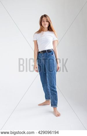 Young Attractive Caucasian Woman With Long Hair In T-shirt And Blue Jeans Isolated On White Studio B