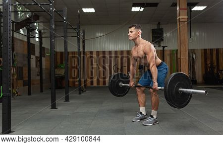 Muscular Bodybuilding Man Doing Deadlift Exercise With A Heavy Barbell In A Modern Health Club. Body