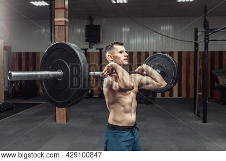 Athletic Muscular Man Exercising With A Heavy Barbell In A Modern Health Club. Bodybuilding And Fitn