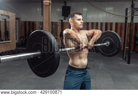 Athletic Muscular Man Exercising With A Heavy Barbell In A Modern Health Club. Bodybuilding And Fitn