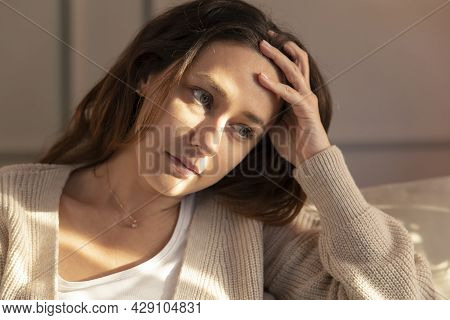 Young Woman Lying At Home In Living Room Sitting On Sofa. She Feeling Sad And Worried Suffering Depr