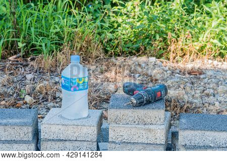 Cordless Power Drill On Stack Of Bricks Beside Bottle Of Mineral Water.