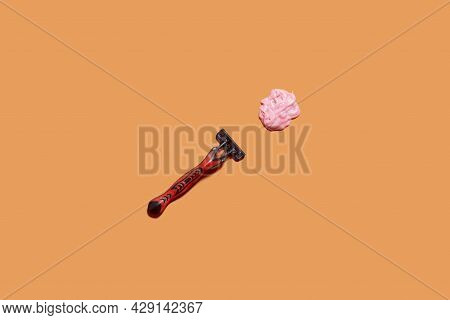 Shaving Foam Gel And Razor On Orange Background. A Multiple Use Shaving Razor And Cream. View From A