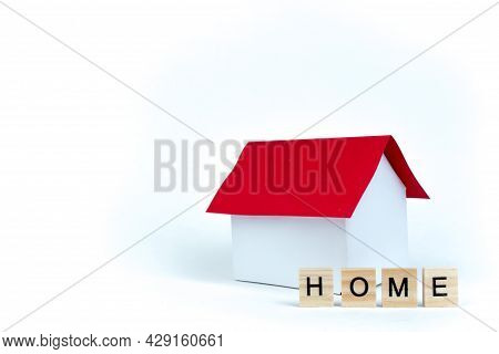 Home- Word Composed Fromwooden Blocks Letters On Red Background, Layout Of A House With A Red Roof. 