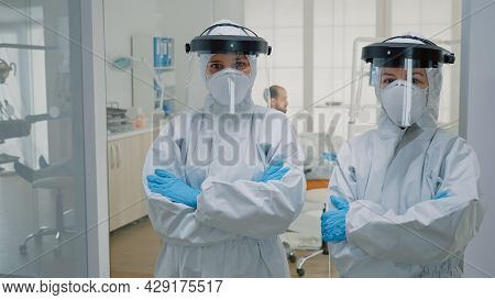 Professional Team Of Dentists In Ppe Suits Standing In Dental Cabinet Looking At Camera. Stomatologi