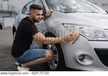 Hand Of Man Wipes Headlight Of His Car Using Rug. Self-service Car Wash. Outdoor