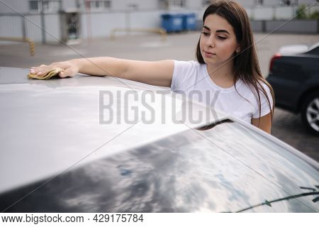Attractive Happy Joyful Female Driver Wipe Windshield On Her Car Using Rag In Self-service Car Wash