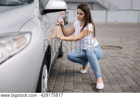 Front View Of Attractive Happy Joyful Female Driver Washing Her Car With Special Rag In Self-service