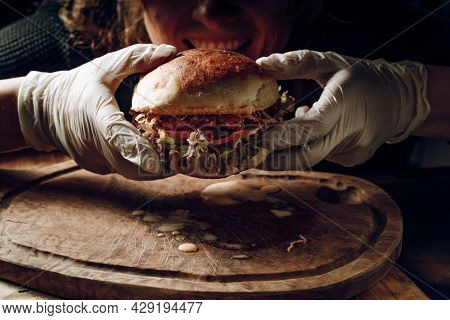 Gloved Hands Take A Hamburer From A Wooden Tray