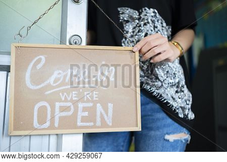 Store Owner Turning Open Sign Broad Through The Door Glass And Ready To Service.