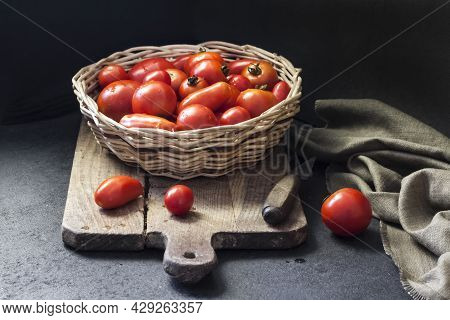 Fresh Red Tomatoes In Whicker Basket On Black Background