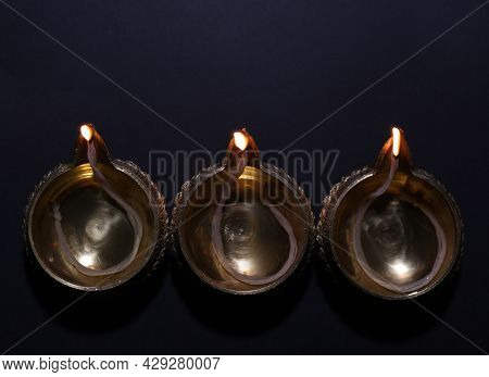 Lit Diyas On Dark Background, Flat Lay. Diwali Lamps