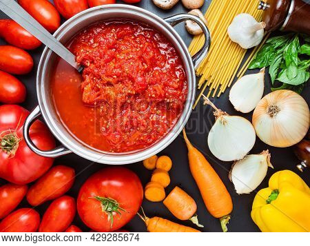 Tomato Sauce And Pasta In The Making: Pot With Mushed Tomatoes And Raw Vegetabless On The Side.