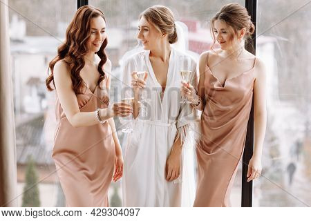 Morning Of Bride. Gorgeous Bride With Best Bridesmaids Are Holding Glasses And Drinking Champagne In