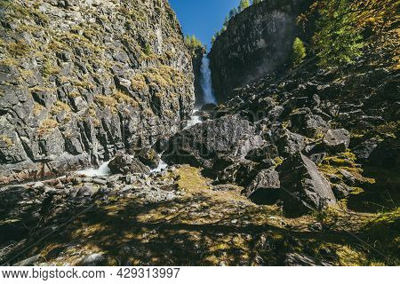 Mountain Autumn Landscape With Vertical Big Waterfall And Yellow Larch Trees. Large Waterfall In Nar