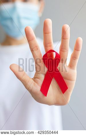 Hand Holding Red Ribbon For December World Aids Day (acquired Immune Deficiency Syndrome), Multiple 