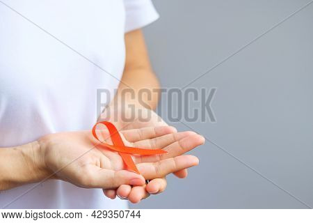 Hand Holding Orange Ribbon For Leukemia, Kidney Cancer Day, World Multiple Sclerosis, Crps, Self Inj