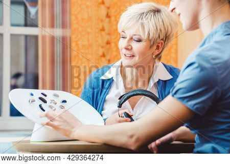 Senior woman with impairment choosing hearing aid