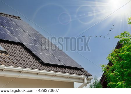 Solar Panels On Houseroof Of Blue Sky With Sun.