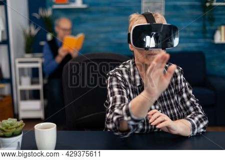 Happy Senior Woman Wearing Virtual Reality Headset Doing Hand Gesture. Cheerful Elderly Woman Experi