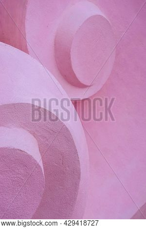 Detail Of Volume Stone Sculpture With Twirl Shapes. Pink Concrete Convex Background