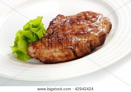 Gegrilltes Schweinesteak auf einem weißen Teller
